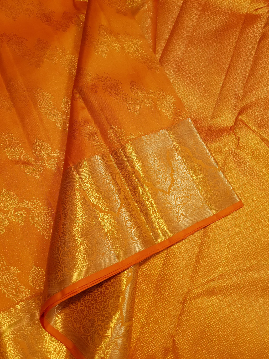 Exquisite Orange Kanchipuram handloom silk saree with intricate gold zari detailing, styled for a traditional wedding look.
