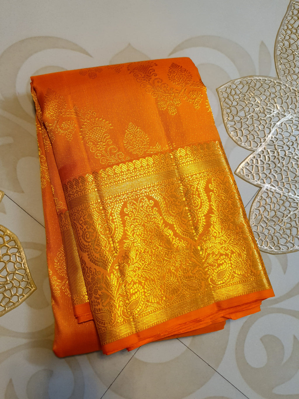 Exquisite Orange Kanchipuram handloom silk saree with intricate gold zari detailing, styled for a traditional wedding look.