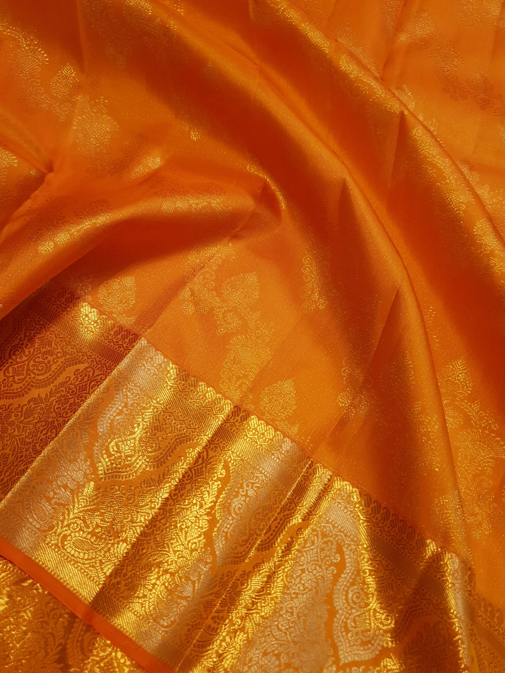 Exquisite Orange Kanchipuram handloom silk saree with intricate gold zari detailing, styled for a traditional wedding look.