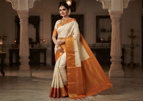 A graceful model wearing a cream and orange Kanchipuram handloom 2G gold korvai silk saree featuring traditional gold zari weaving and classic paisley buttis.