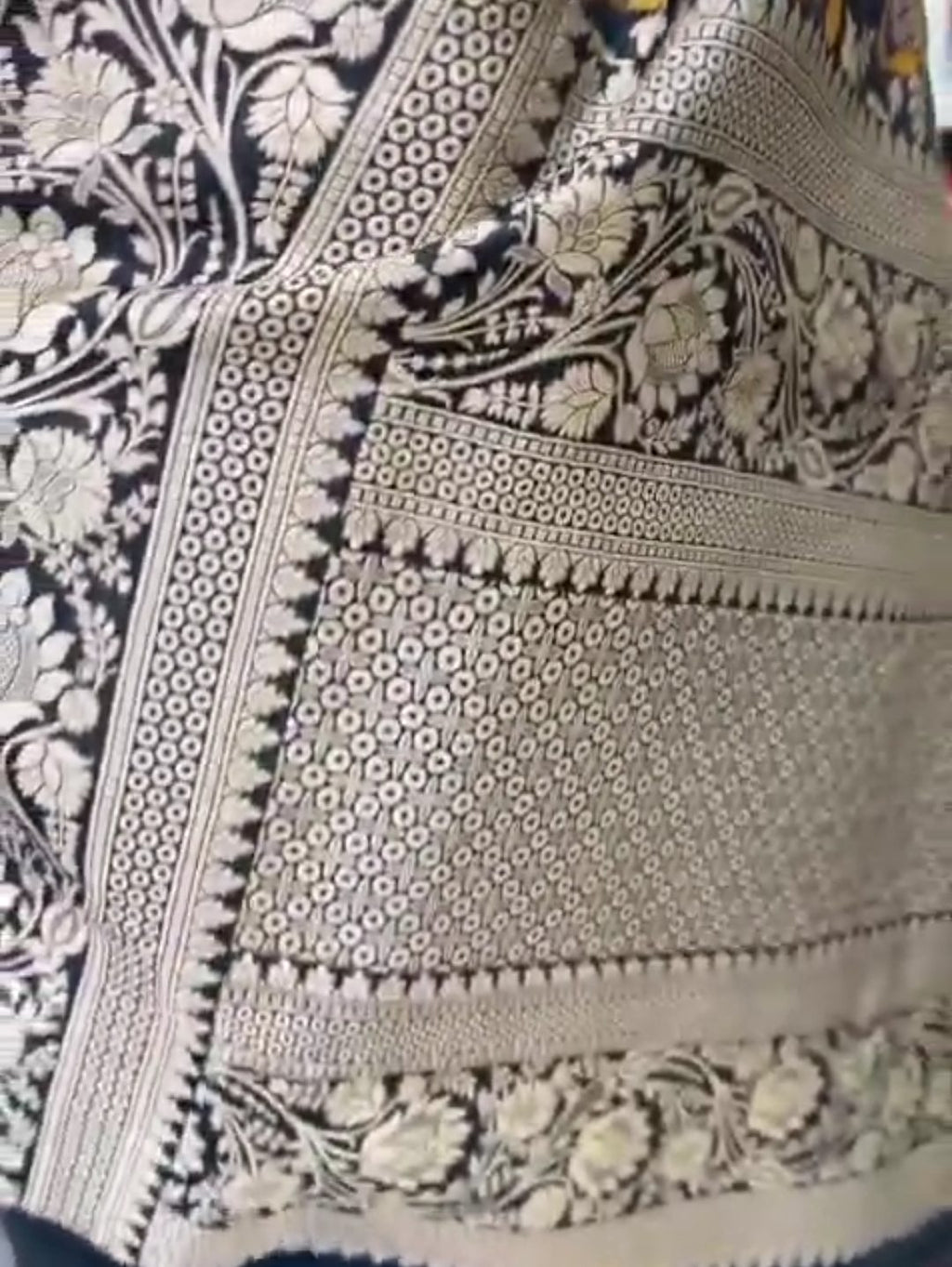 A royal black Banarasi Katan silk saree featuring colorful Tilfi Meenakari floral buttas and an intricate gold zari border.