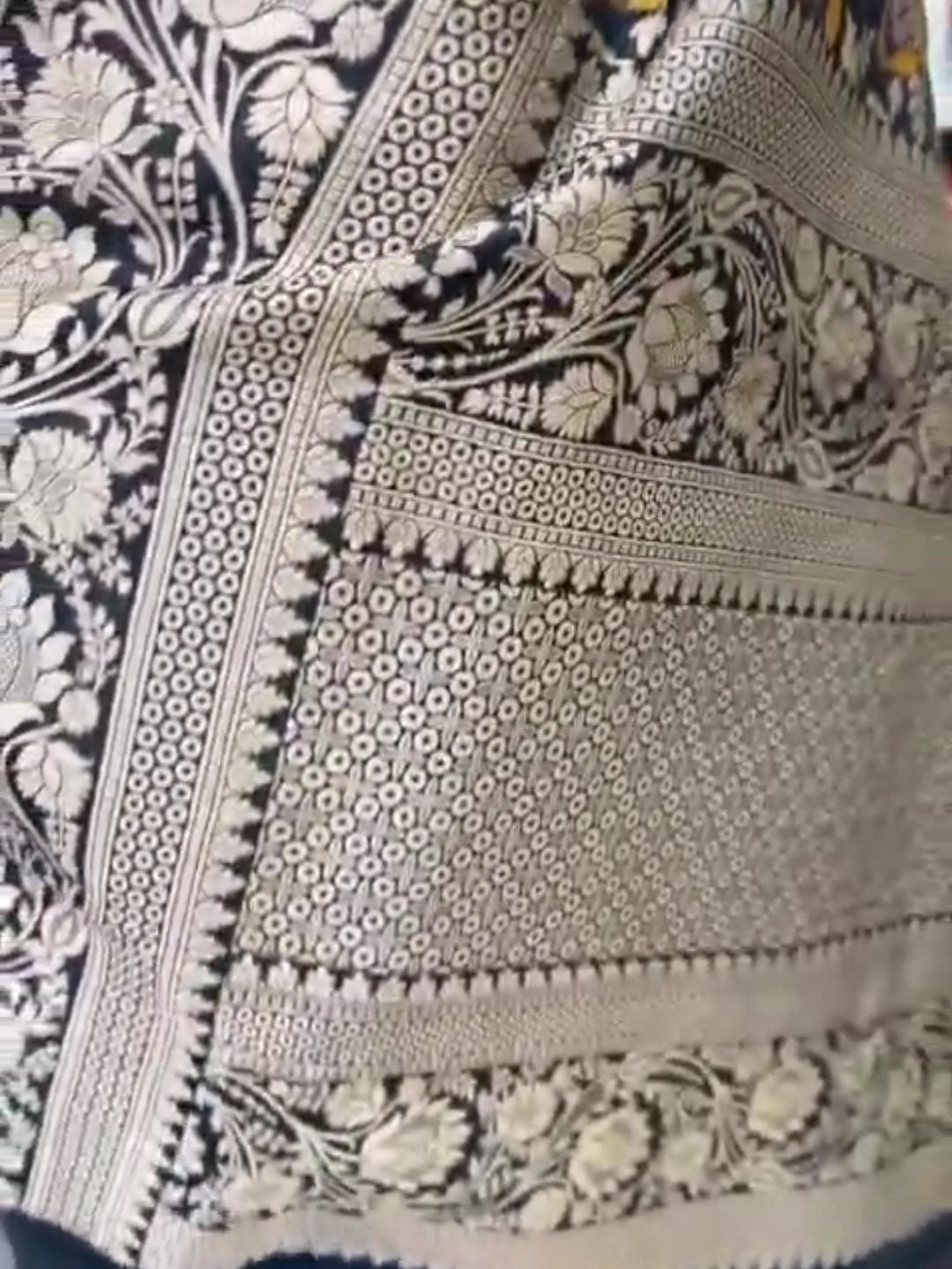 A royal black Banarasi Katan silk saree featuring colorful Tilfi Meenakari floral buttas and an intricate gold zari border.
