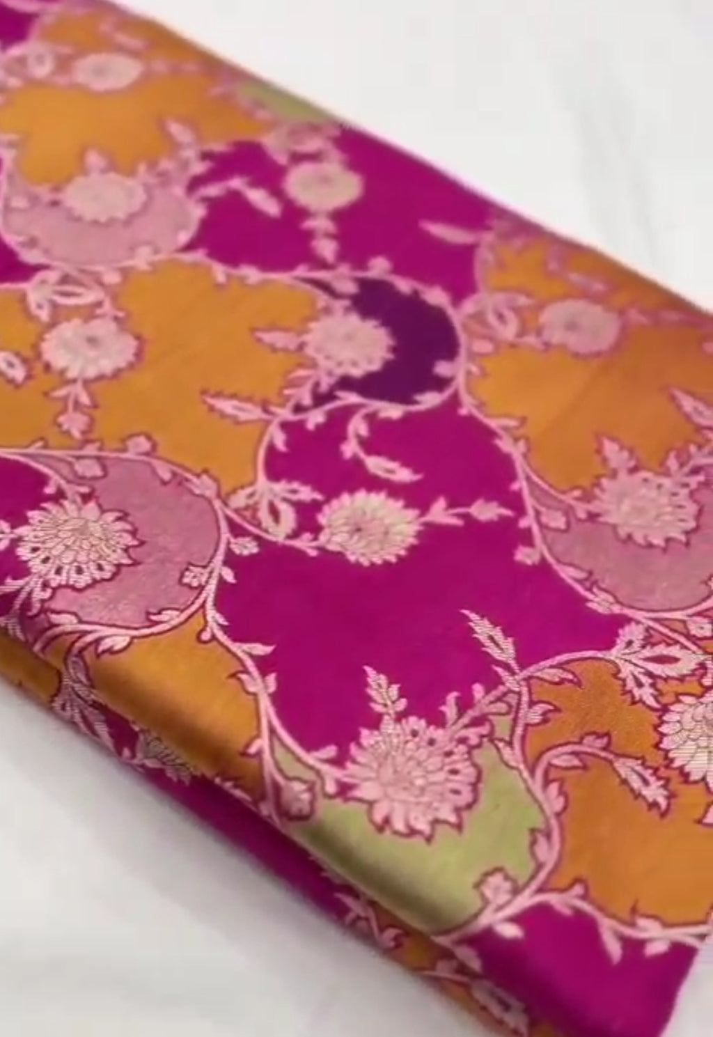 A vibrant hot pink Banarasi Katan silk saree featuring hand-woven Rangkaat diagonal color blocks and intricate Meenakari floral vines in shimmering gold zari.