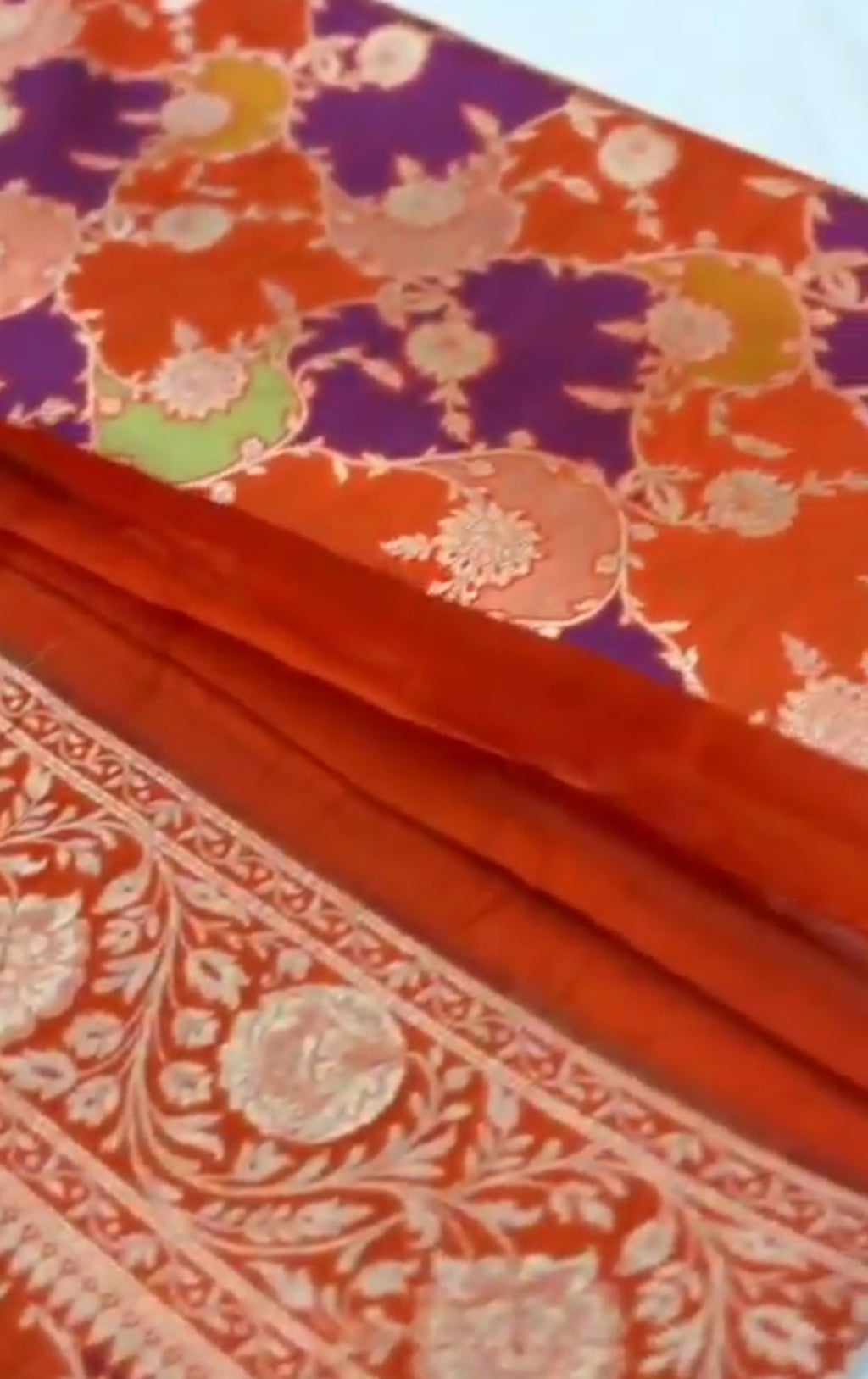 A vibrant chilly red Banarasi Katan silk saree featuring rare Rangkaat diagonal color blocking and multi-hued Meenakari floral weaving.