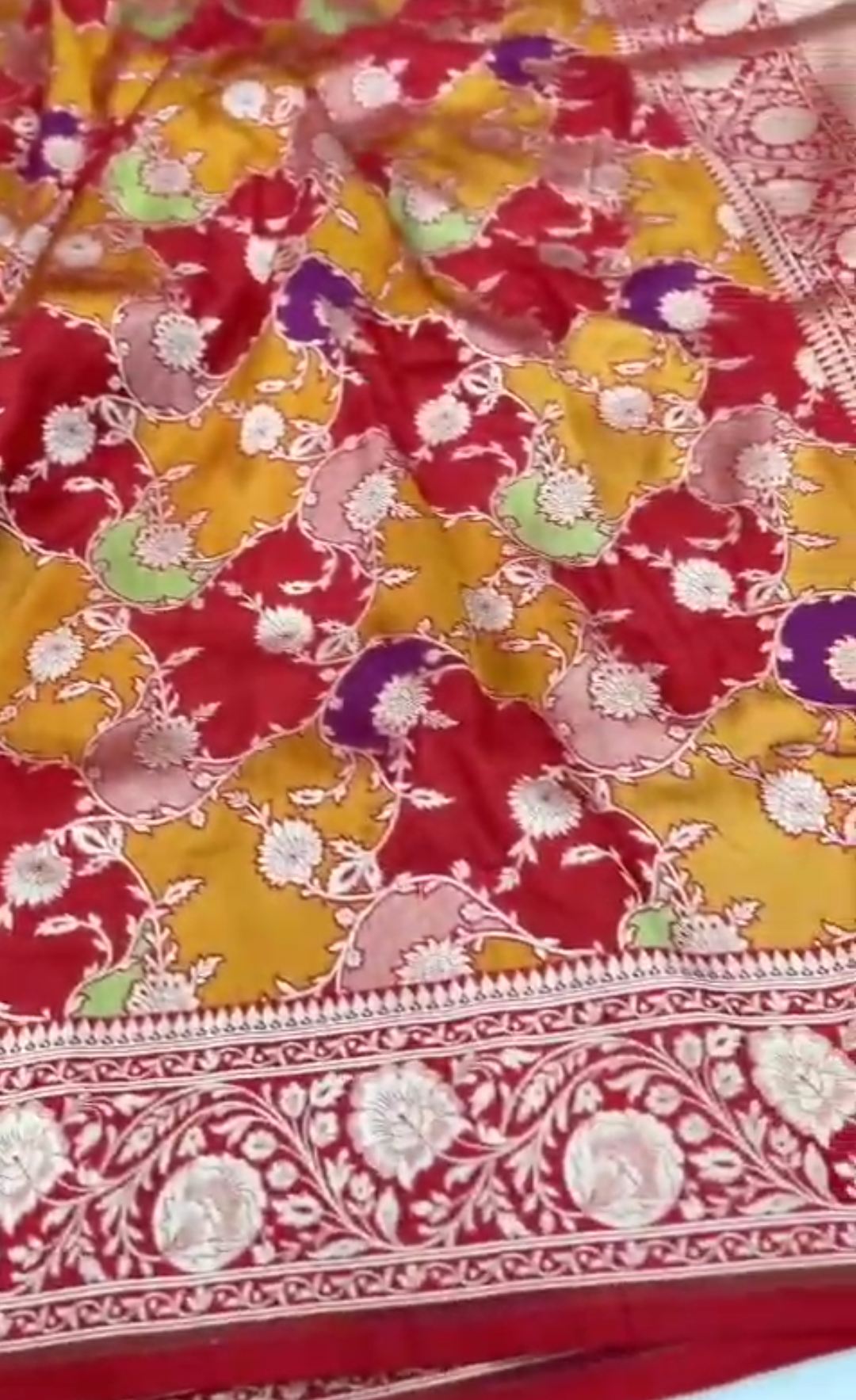 A majestic red Banarasi Katan silk saree with Rangkaat multi-color diagonal patterns and intricate hand-woven Meenakari floral jal.