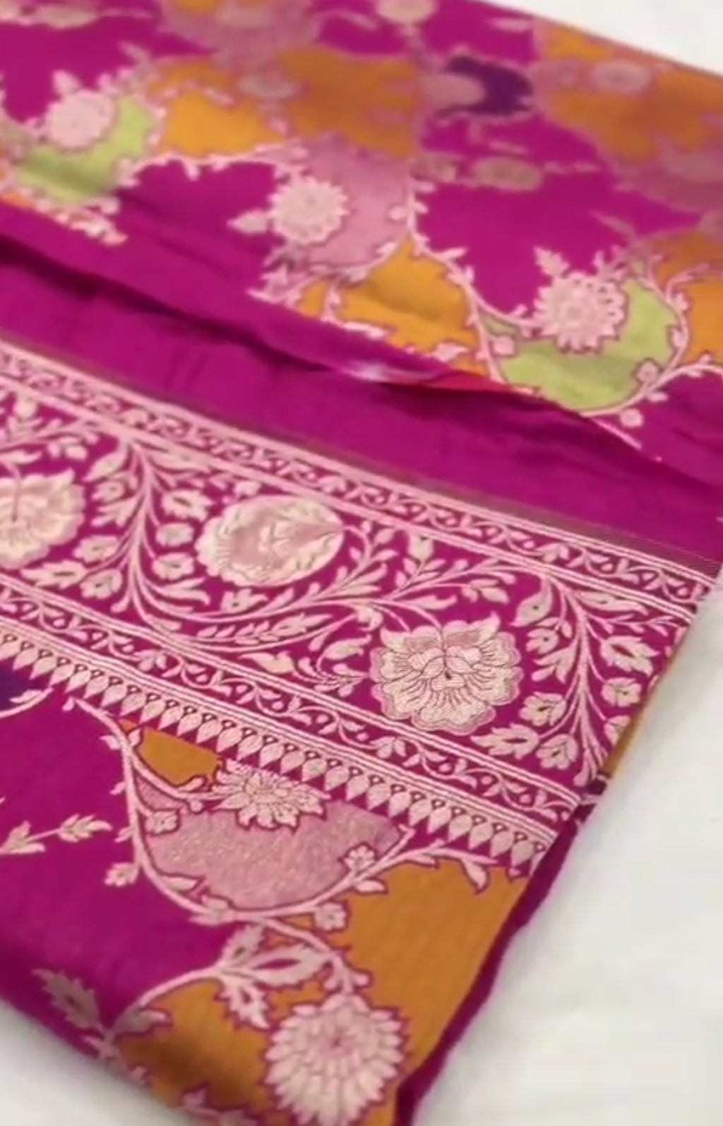 A vibrant hot pink Banarasi Katan silk saree featuring hand-woven Rangkaat diagonal color blocks and intricate Meenakari floral vines in shimmering gold zari.