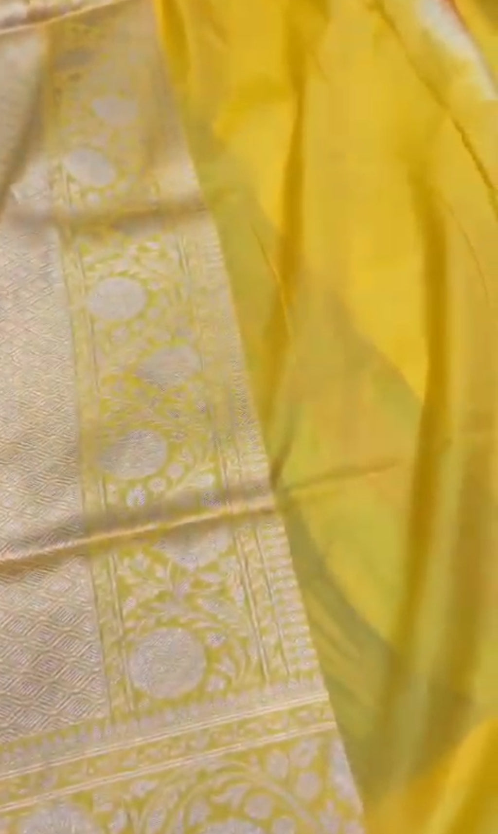 A luminous golden yellow Banarasi Katan silk saree with hand-woven Rangkaat diagonal patterns and vibrant multi-colored Meenakari floral vines.