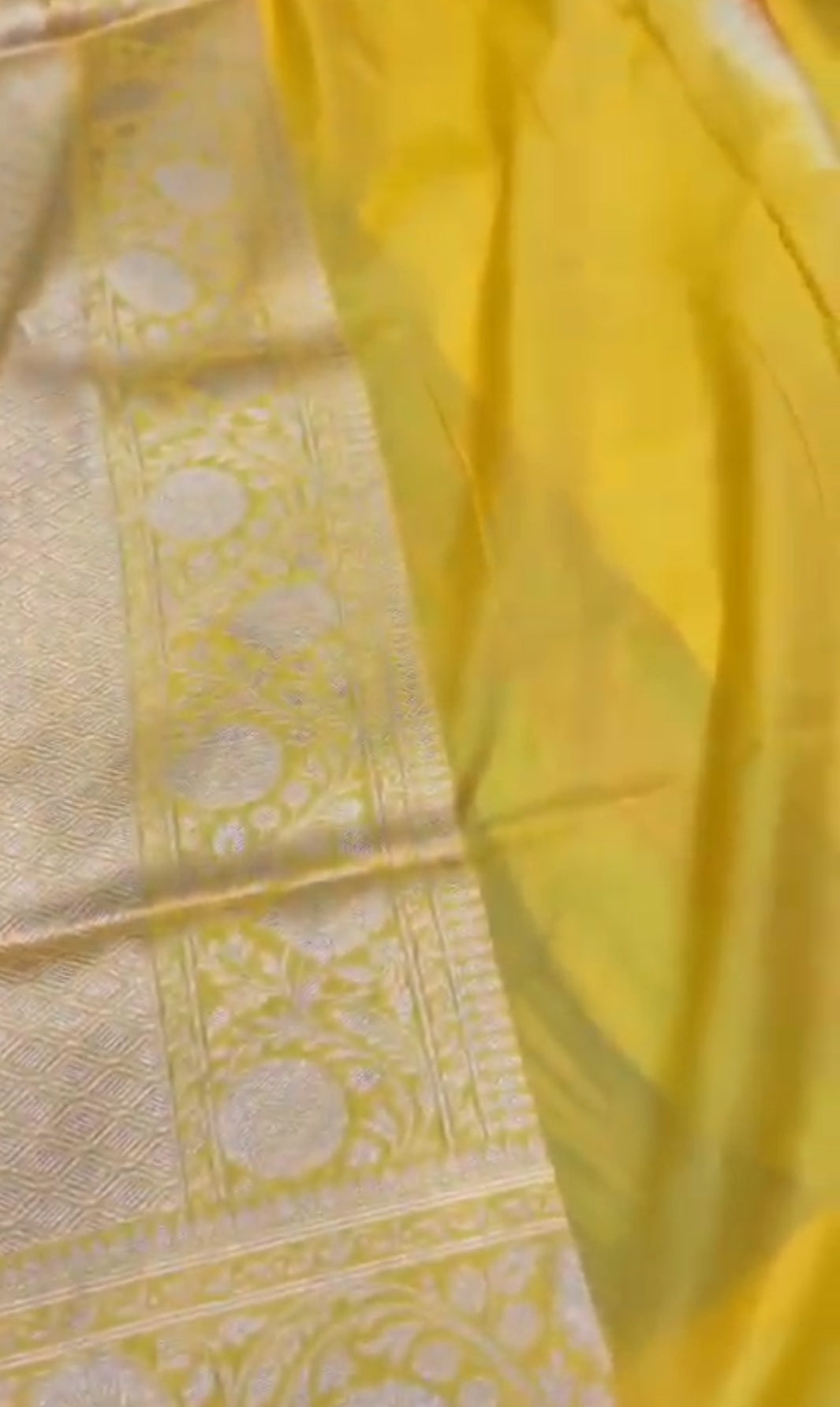 A luminous golden yellow Banarasi Katan silk saree with hand-woven Rangkaat diagonal patterns and vibrant multi-colored Meenakari floral vines.