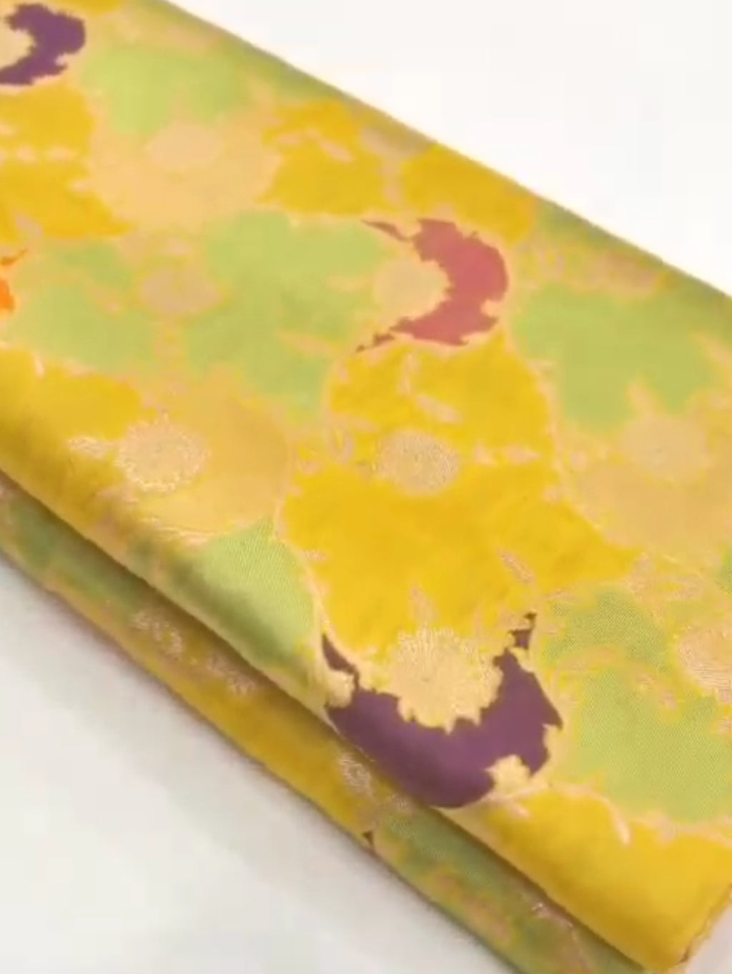 A luminous golden yellow Banarasi Katan silk saree with hand-woven Rangkaat diagonal patterns and vibrant multi-colored Meenakari floral vines.