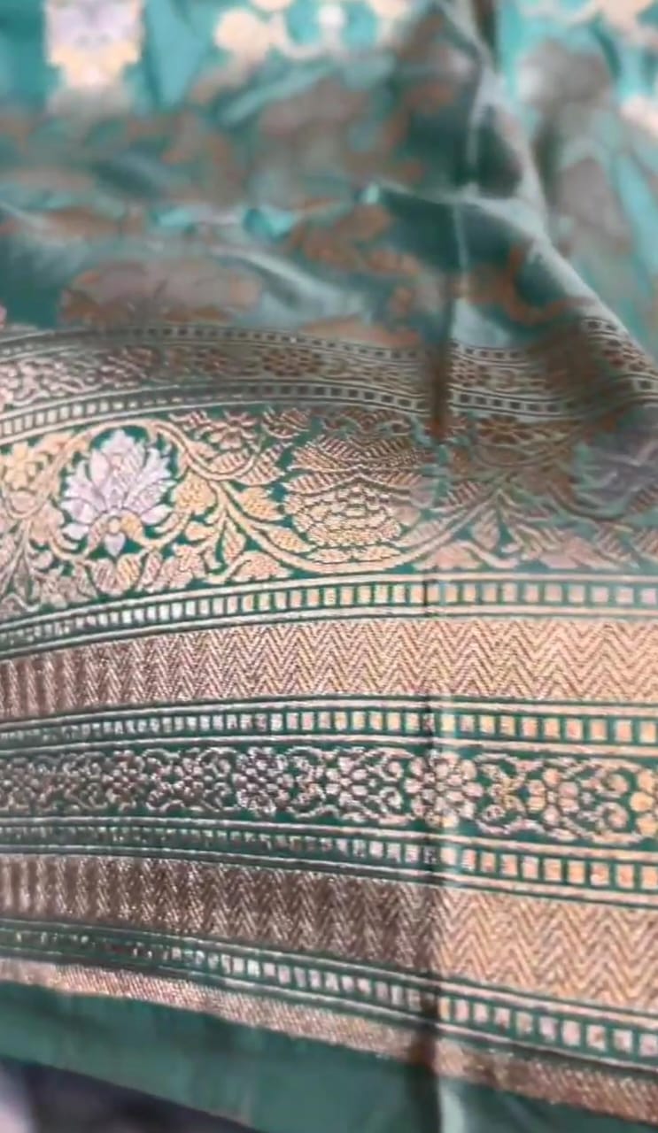 A vibrant turquoise Banarasi Katan silk saree with hand-woven Sona Rupa gold and silver zari floral motifs and an ornate border.