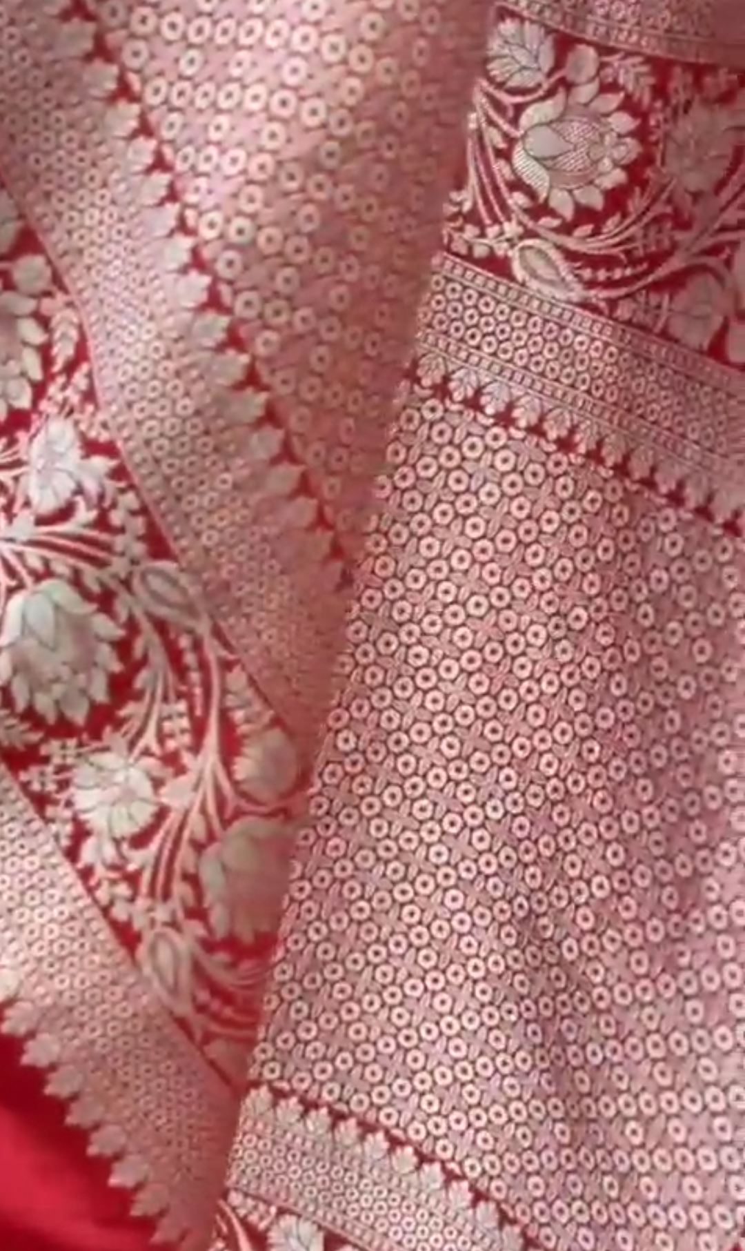 A bright bridal red Banarasi Katan silk saree adorned with colorful Tilfi Meenakari floral buttas and a heavy gold zari border.