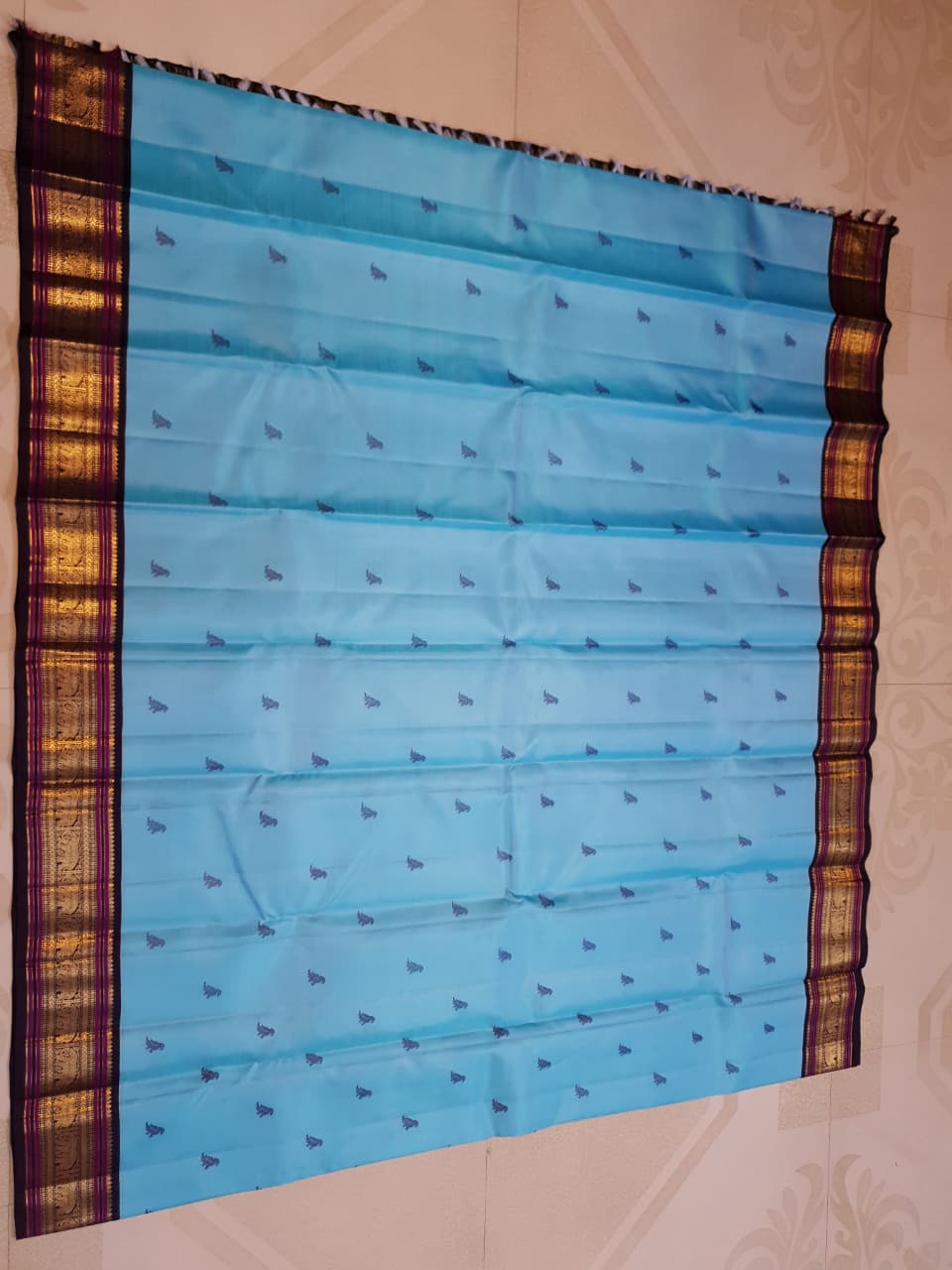 A elegant drape of a turquoise Kanchipuram Korvai silk saree showcasing the intricate interlocking border design and 3G gold zari details.