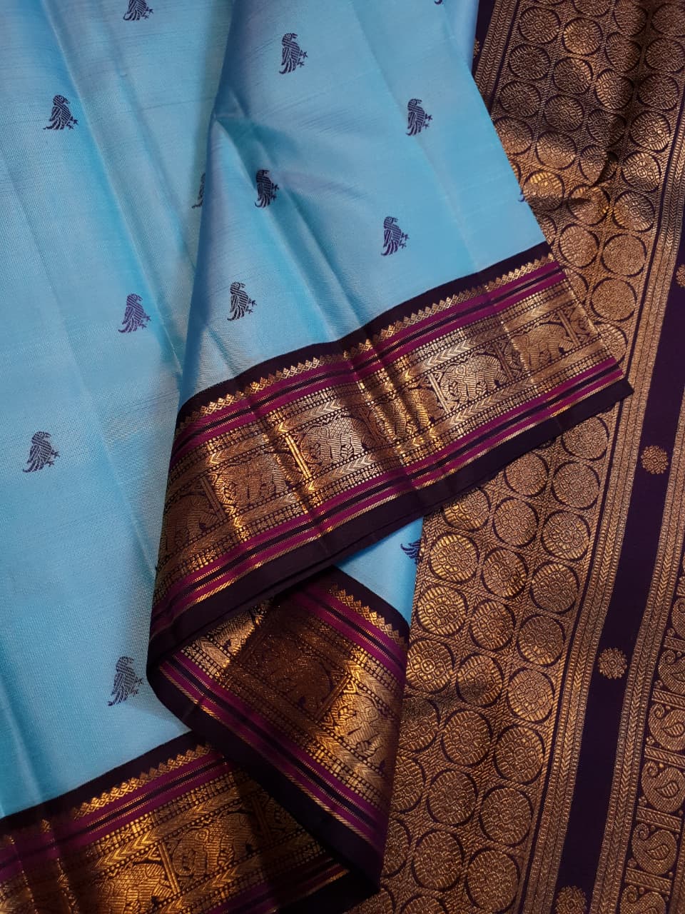 A elegant drape of a turquoise Kanchipuram Korvai silk saree showcasing the intricate interlocking border design and 3G gold zari details.