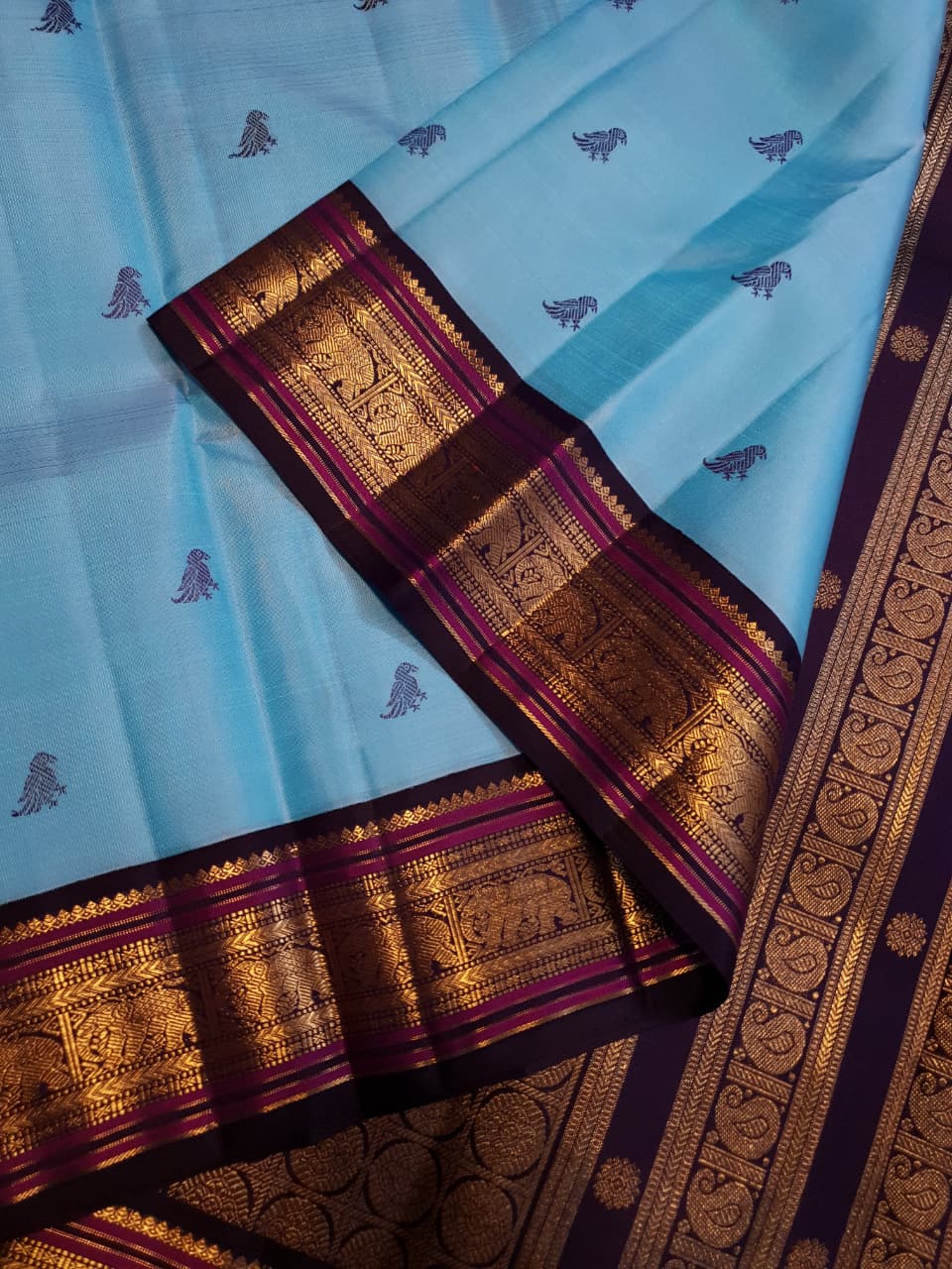 A elegant drape of a turquoise Kanchipuram Korvai silk saree showcasing the intricate interlocking border design and 3G gold zari details.