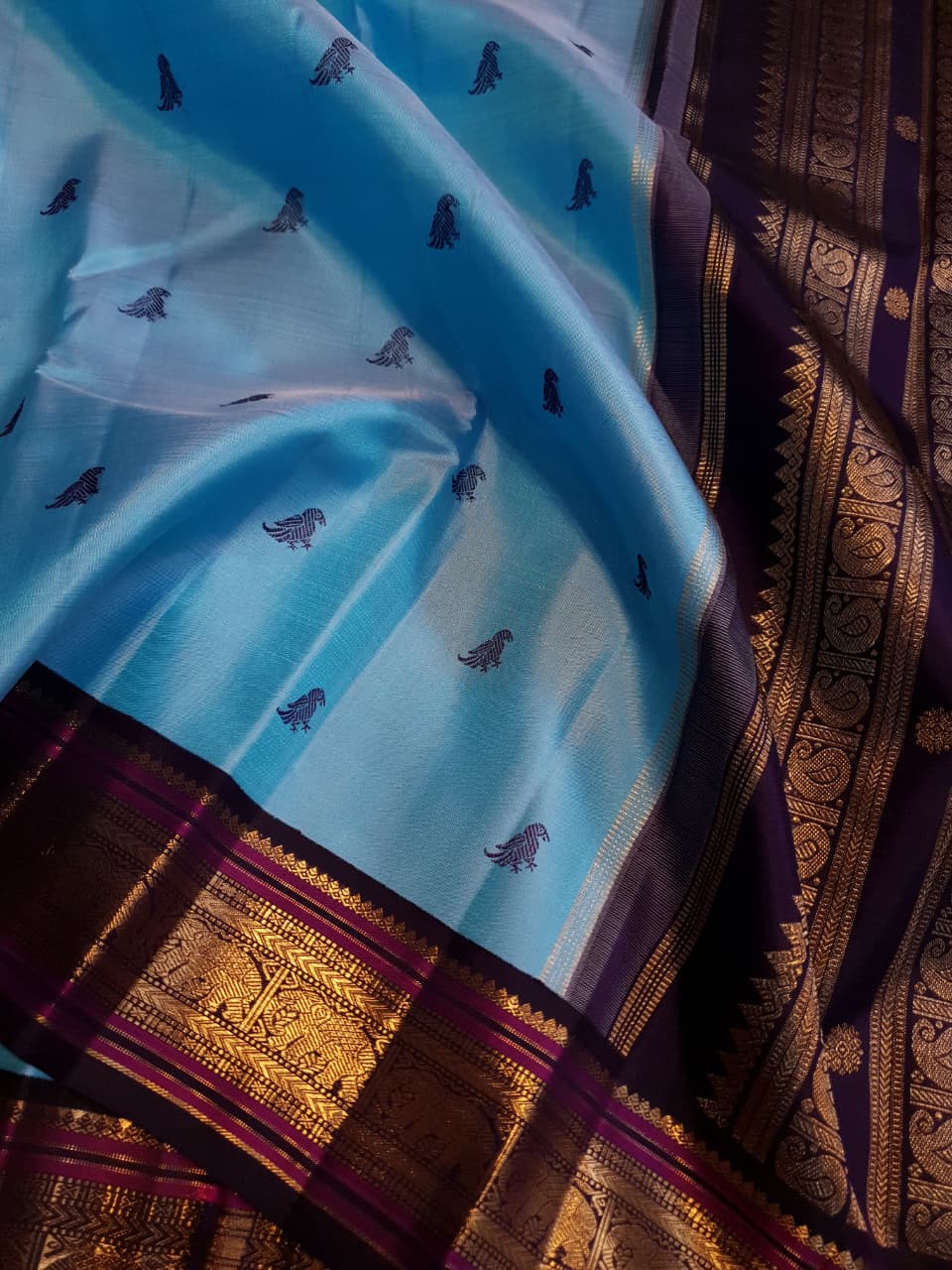 A elegant drape of a turquoise Kanchipuram Korvai silk saree showcasing the intricate interlocking border design and 3G gold zari details.