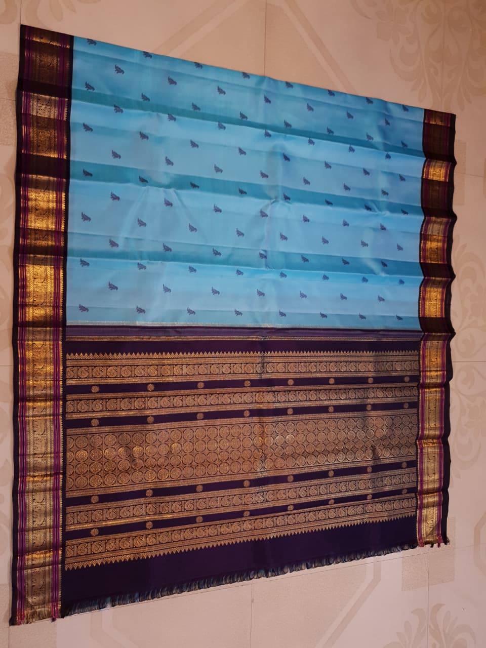 A elegant drape of a turquoise Kanchipuram Korvai silk saree showcasing the intricate interlocking border design and 3G gold zari details.
