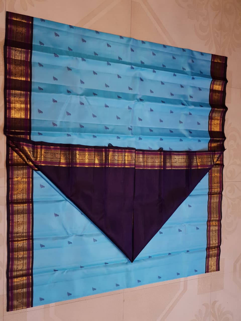 A elegant drape of a turquoise Kanchipuram Korvai silk saree showcasing the intricate interlocking border design and 3G gold zari details.