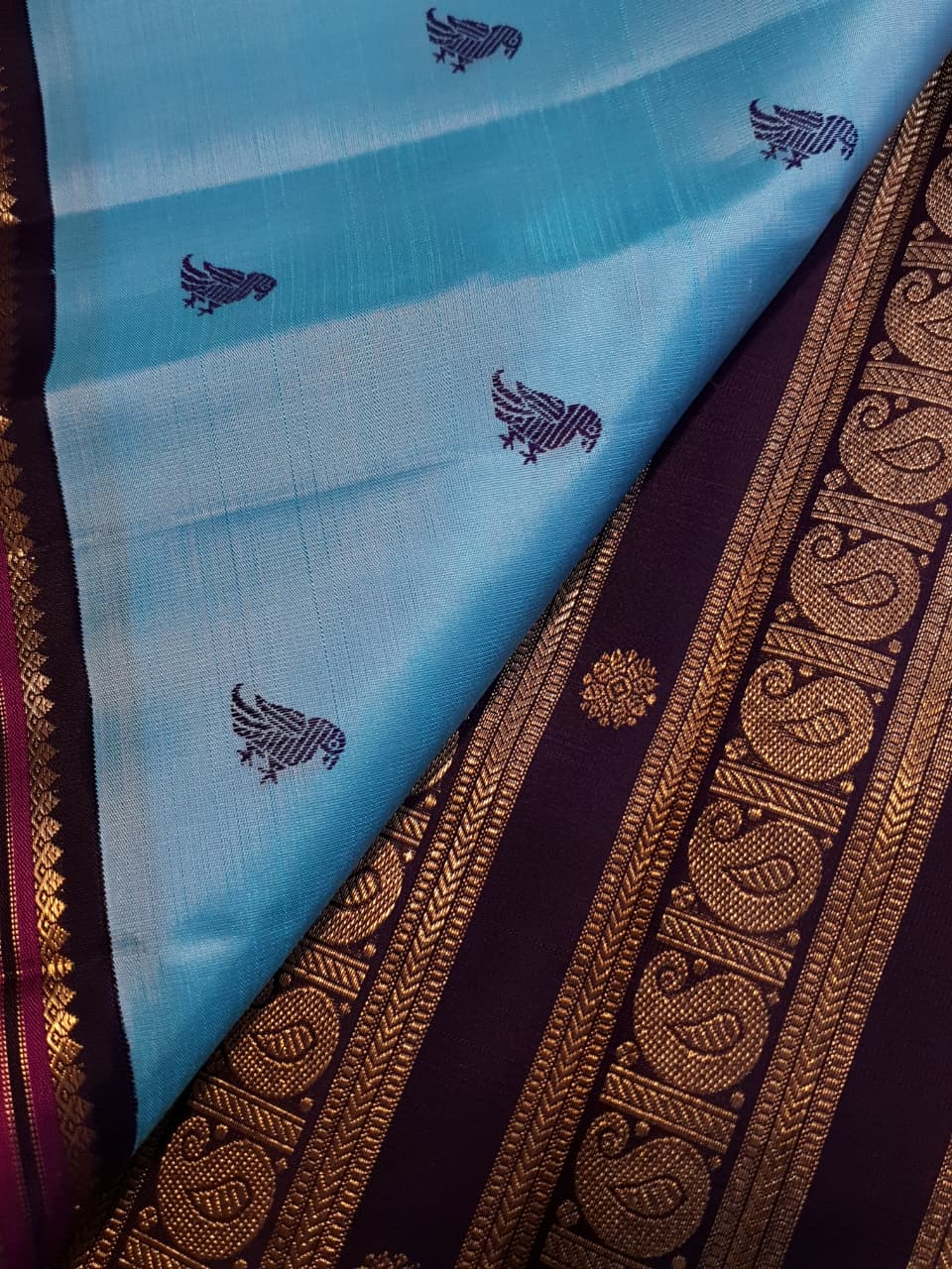 A elegant drape of a turquoise Kanchipuram Korvai silk saree showcasing the intricate interlocking border design and 3G gold zari details.