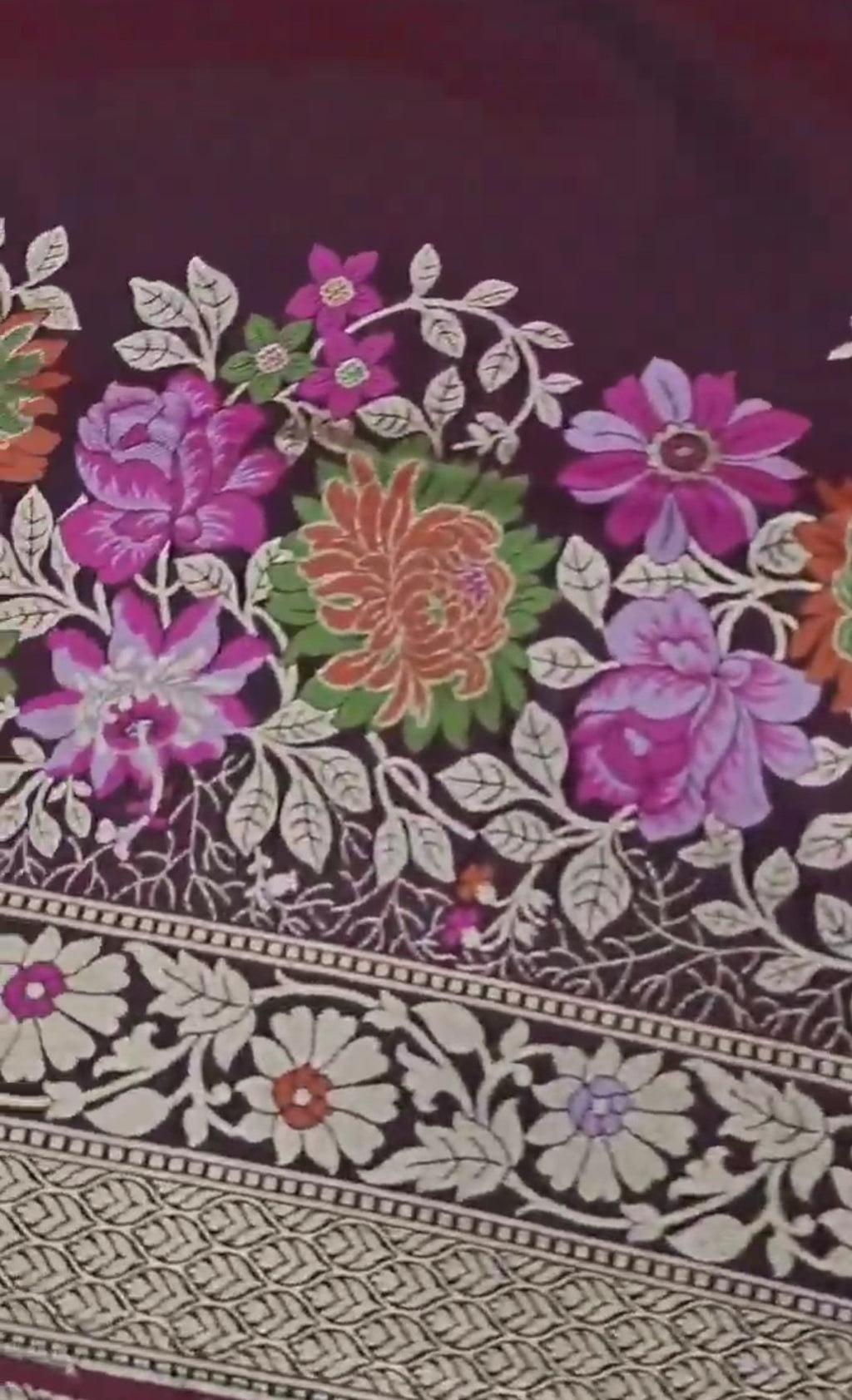 A deep wine-colored Banarasi semi Katan silk saree with a minimalist plain body, intricate Tilfi Meenakari floral borders, and a heavy gold zari blouse.