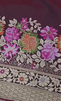 A deep wine-colored Banarasi semi Katan silk saree with a minimalist plain body, intricate Tilfi Meenakari floral borders, and a heavy gold zari blouse.