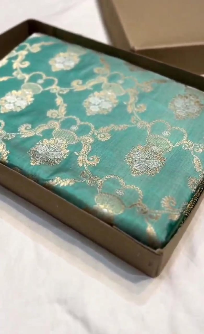 A vibrant turquoise Banarasi Katan silk saree with hand-woven Sona Rupa gold and silver zari floral motifs and an ornate border.