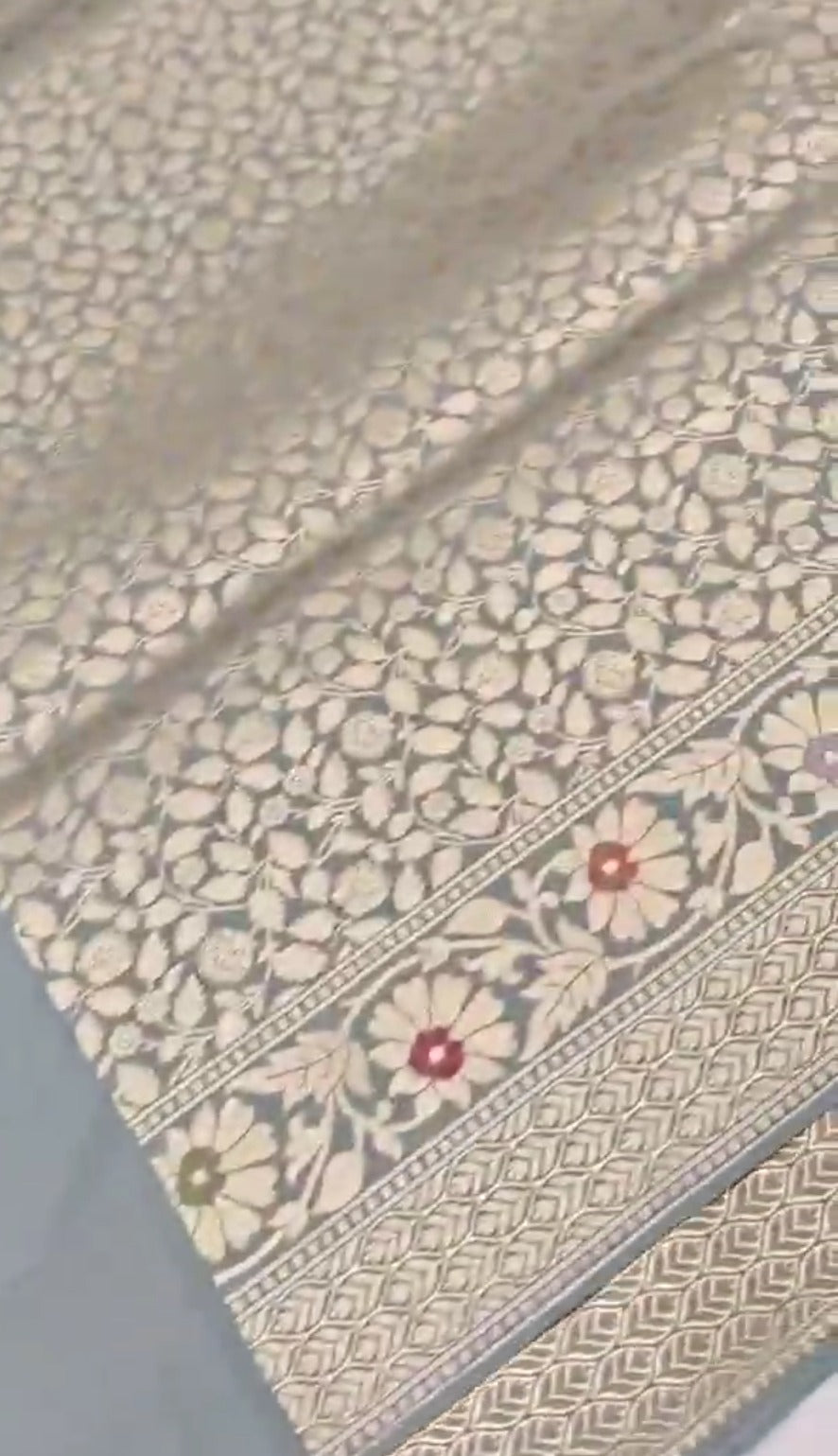 A serene powder blue Banarasi semi Katan silk saree with a plain body, a multi-colored Tilfi Meenakari floral border, and a matching heavy brocade blouse.