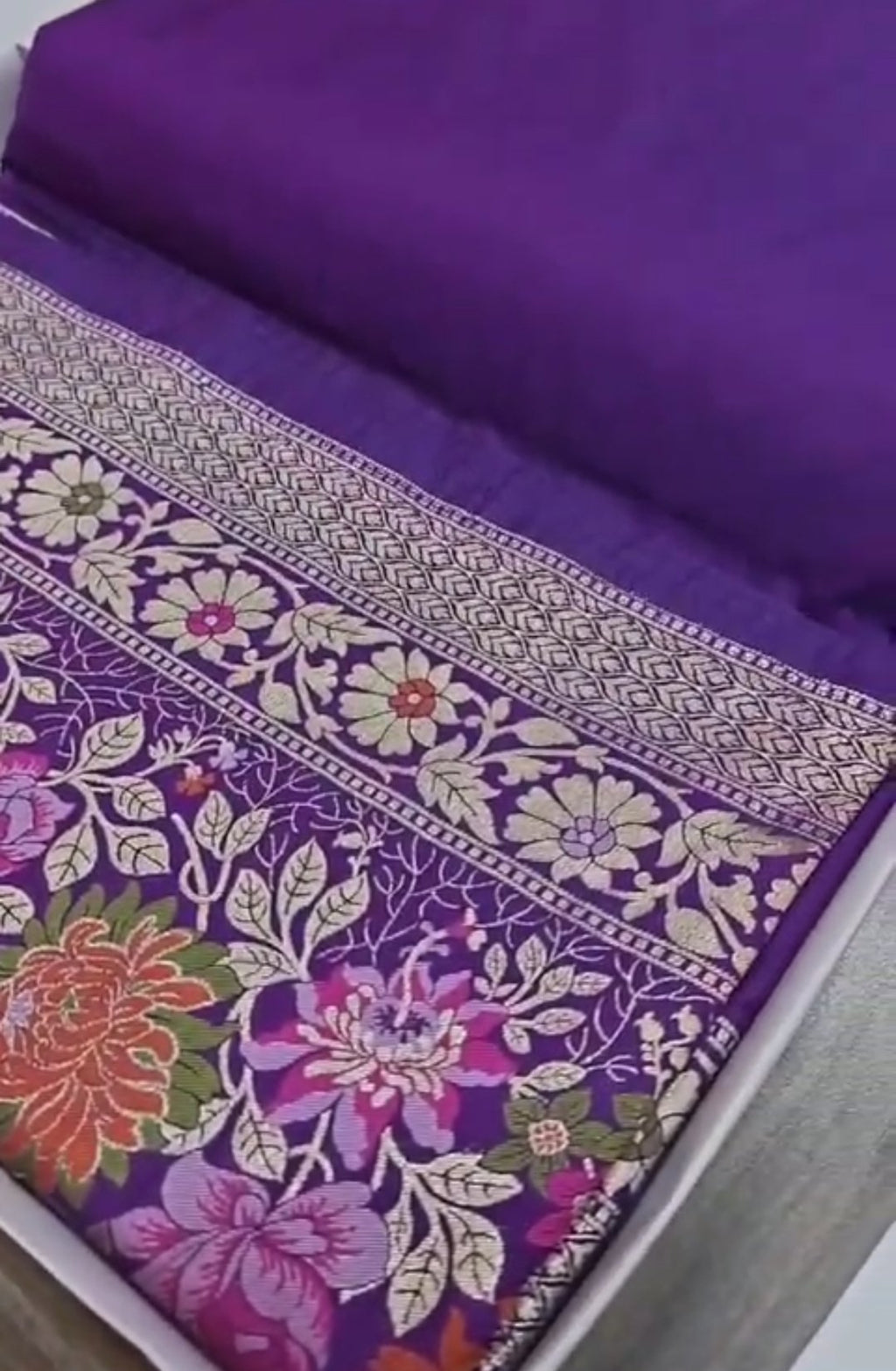 A soft lilac Banarasi semi Katan silk saree with a minimalist plain body, intricate multi-colored Tilfi Meenakari floral borders, and a matching gold zari brocade blouse.