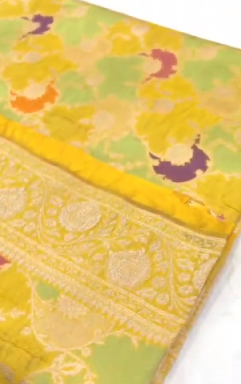 A luminous golden yellow Banarasi Katan silk saree with hand-woven Rangkaat diagonal patterns and vibrant multi-colored Meenakari floral vines.