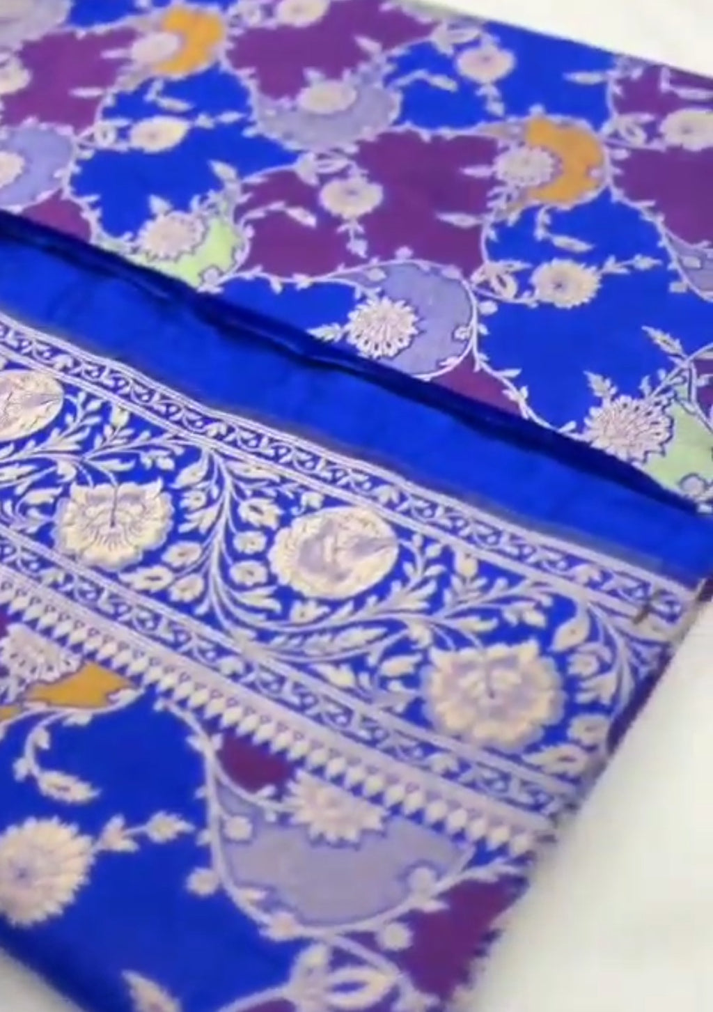 A deep azure blue Banarasi Katan silk saree featuring hand-woven Rangkaat diagonal color blocks and intricate Meenakari floral vines in gold zari.