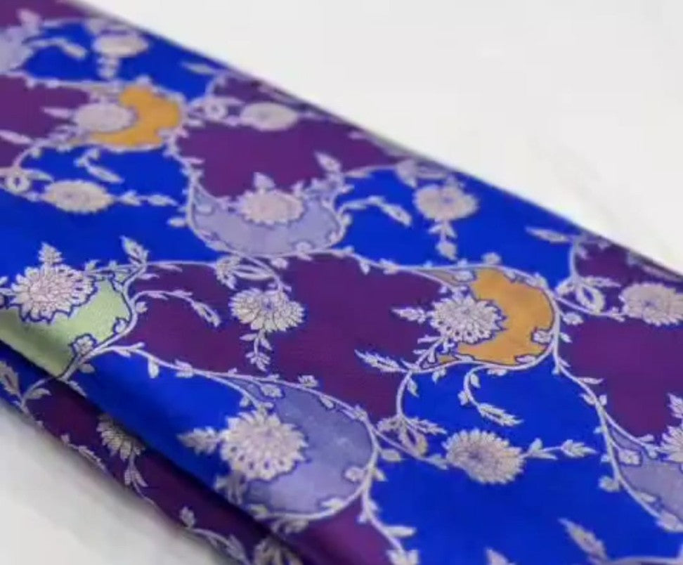 A deep azure blue Banarasi Katan silk saree featuring hand-woven Rangkaat diagonal color blocks and intricate Meenakari floral vines in gold zari.