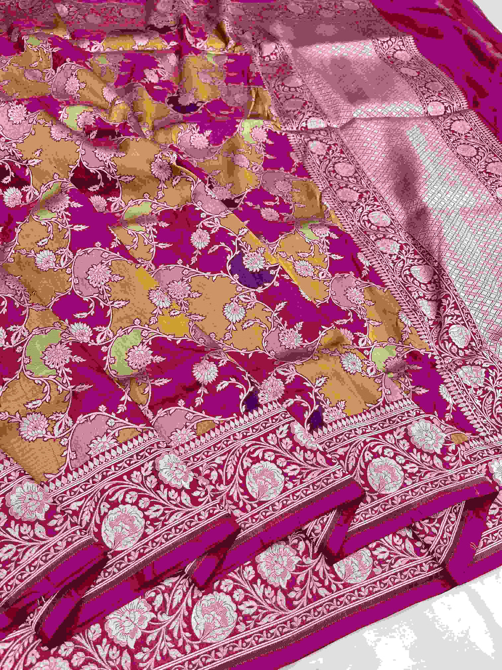 A vibrant hot pink Banarasi Katan silk saree featuring hand-woven Rangkaat diagonal color blocks and intricate Meenakari floral vines in shimmering gold zari.