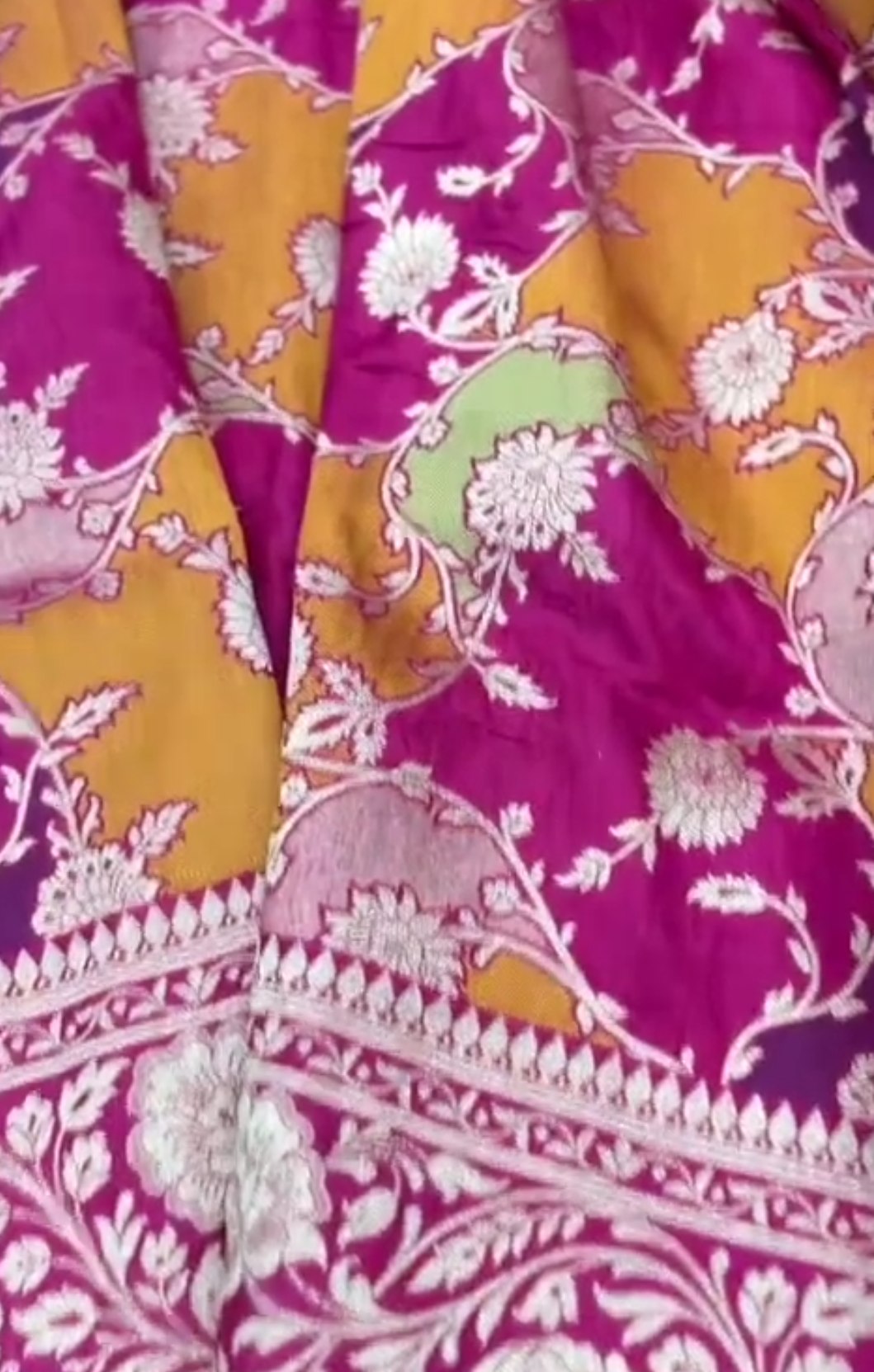 A vibrant hot pink Banarasi Katan silk saree featuring hand-woven Rangkaat diagonal color blocks and intricate Meenakari floral vines in shimmering gold zari.