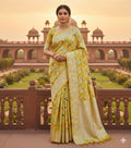 A luminous golden yellow Banarasi Katan silk saree with hand-woven Rangkaat diagonal patterns and vibrant multi-colored Meenakari floral vines.