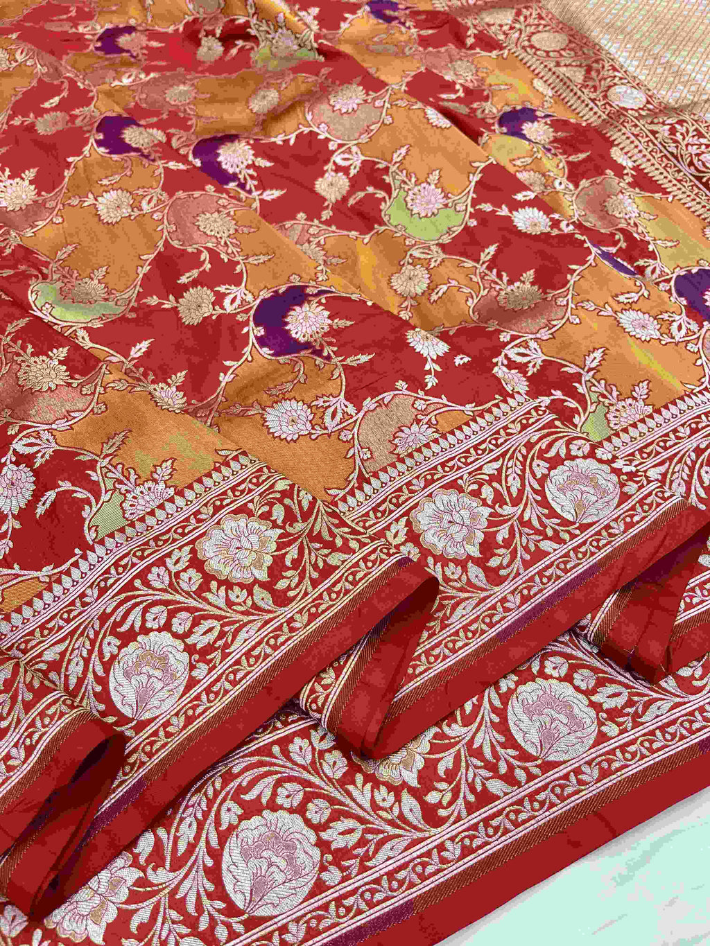 A majestic red Banarasi Katan silk saree with Rangkaat multi-color diagonal patterns and intricate hand-woven Meenakari floral jal.
