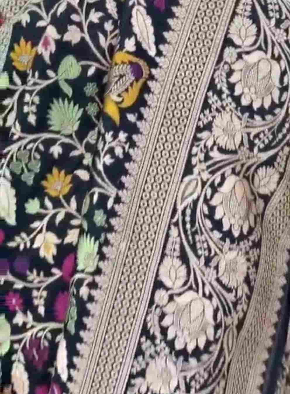 A royal black Banarasi Katan silk saree featuring colorful Tilfi Meenakari floral buttas and an intricate gold zari border.