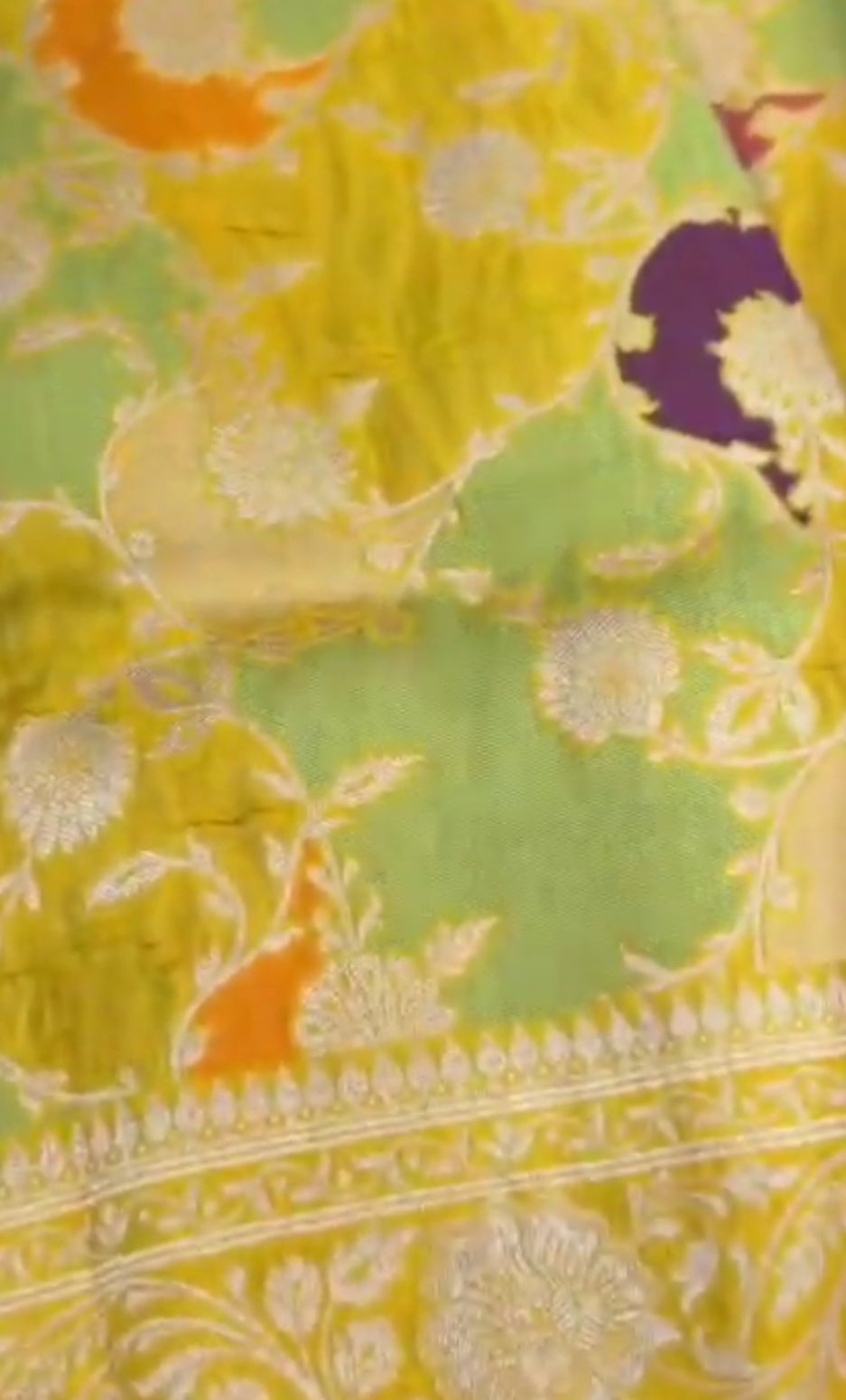A luminous golden yellow Banarasi Katan silk saree with hand-woven Rangkaat diagonal patterns and vibrant multi-colored Meenakari floral vines.