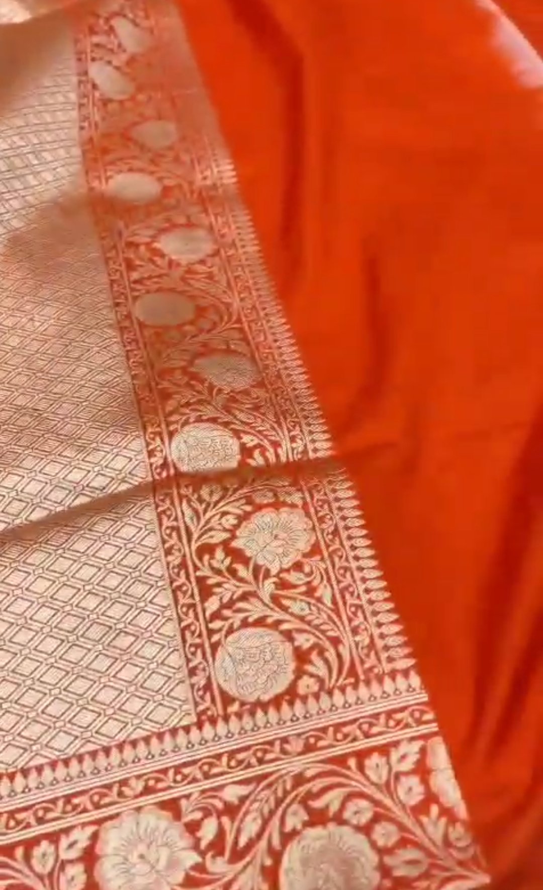 A vibrant chilly red Banarasi Katan silk saree featuring rare Rangkaat diagonal color blocking and multi-hued Meenakari floral weaving.