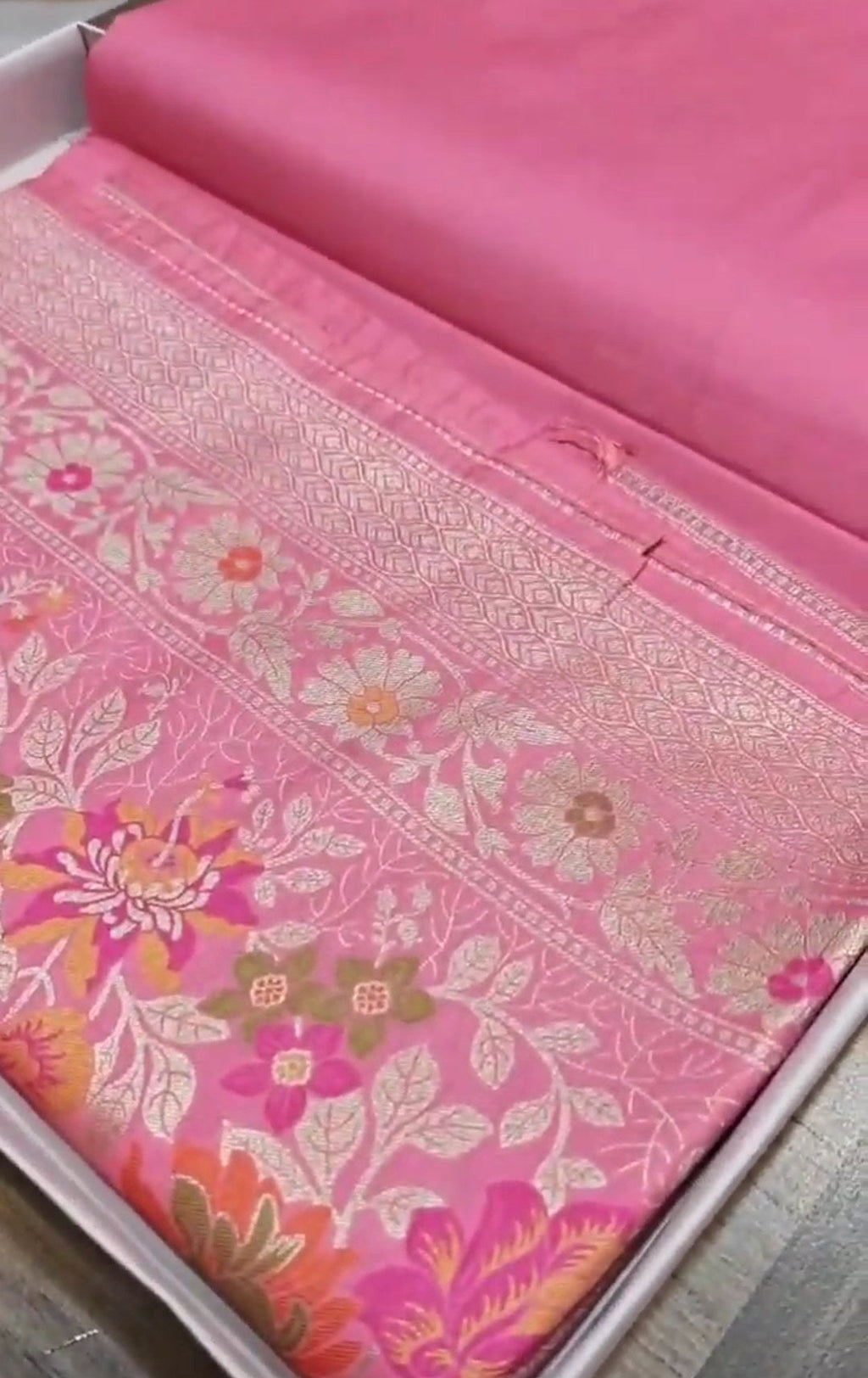 A soft pastel pink Banarasi saree with a plain silk body, a heavy Tilfi Meenakari floral border, and a matching full brocade blouse piece.