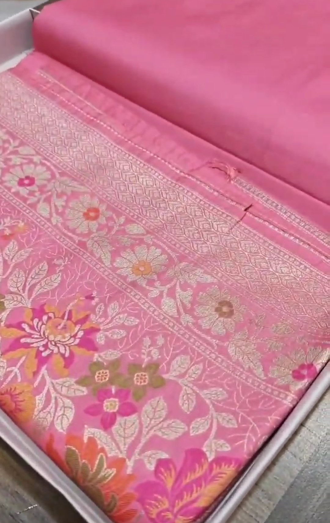 A soft pastel pink Banarasi saree with a plain silk body, a heavy Tilfi Meenakari floral border, and a matching full brocade blouse piece.