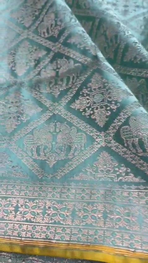 Shop our premium Dual Tone Turquoise Banarasi Handloom Katan Silk Saree. Silk Mark Certified for authenticity, this Shikargah masterpiece features rich silver zari weaving, perfect for weddings and heritage collections.