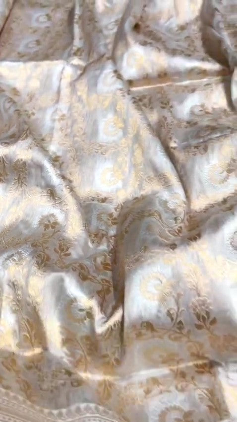 Ivory Banarasi Handloom Katan Silk Sona Rupa Saree with intricate gold zari and silver work in a traditional setting.