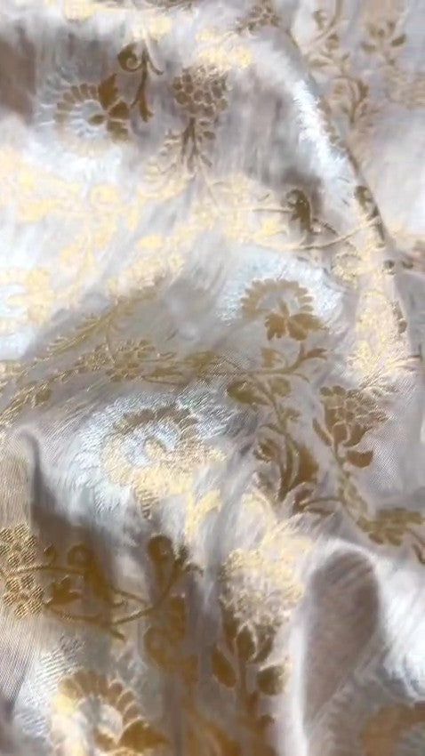 Ivory Banarasi Handloom Katan Silk Sona Rupa Saree with intricate gold zari and silver work in a traditional setting.
