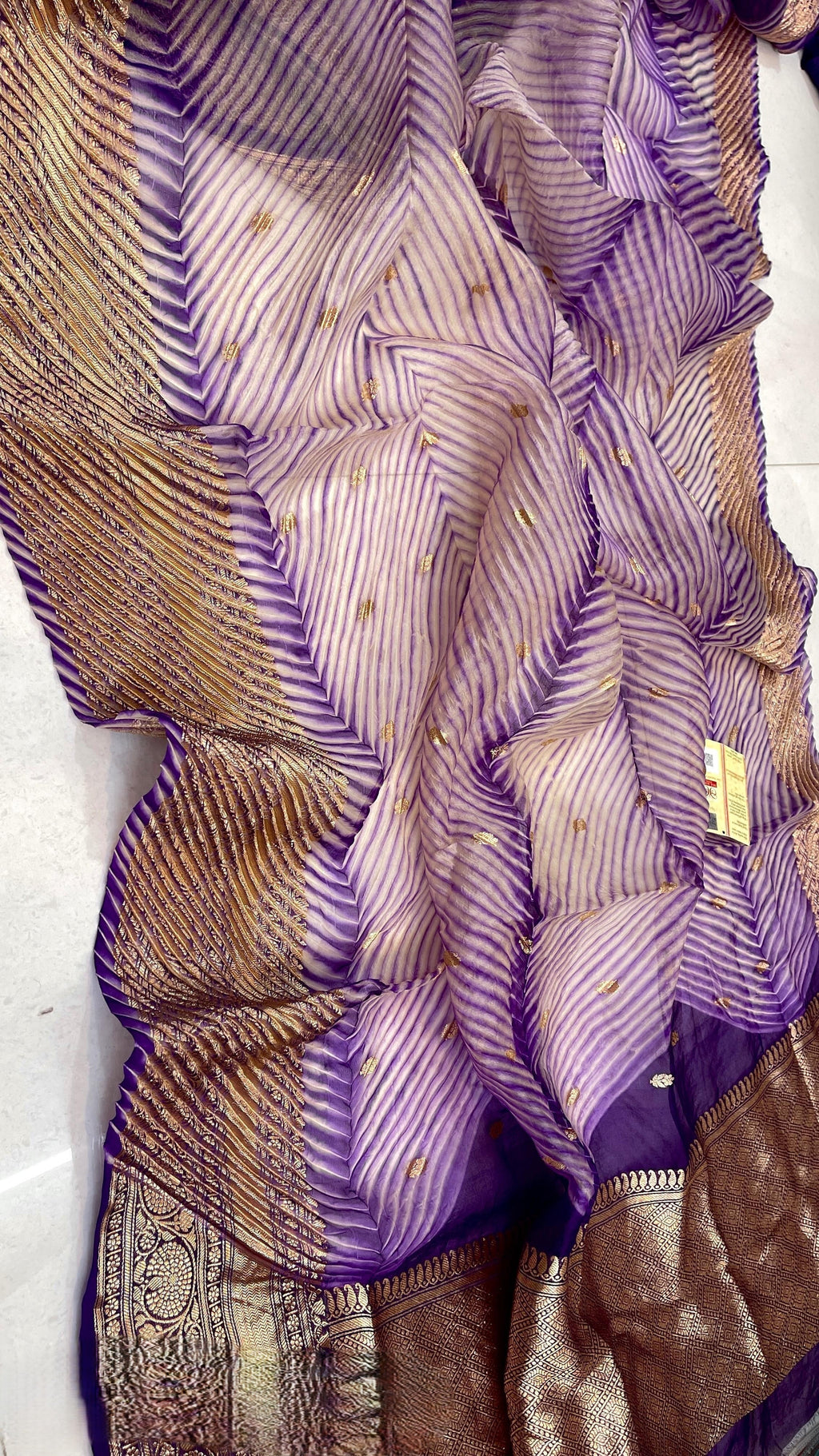 A model wearing a unique lavender and purple hand-dyed diagonal Arasi Shibori Kora Tissue silk saree with elaborate gold zari borders and pallu.