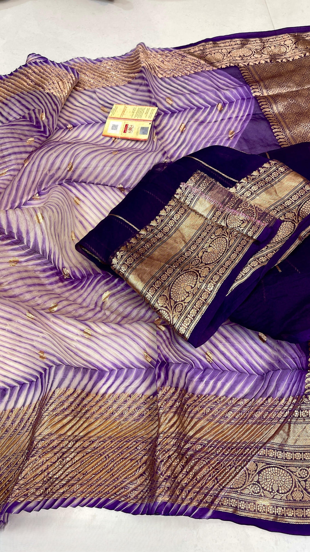 A model wearing a unique lavender and purple hand-dyed diagonal Arasi Shibori Kora Tissue silk saree with elaborate gold zari borders and pallu.