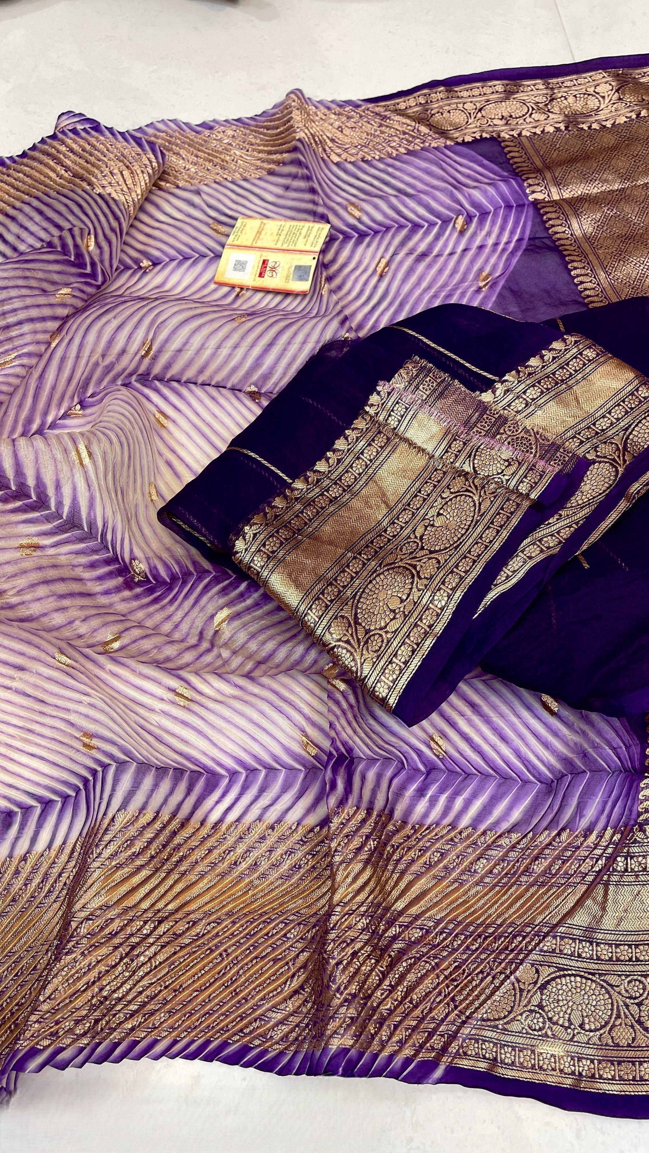 A model wearing a unique lavender and purple hand-dyed diagonal Arasi Shibori Kora Tissue silk saree with elaborate gold zari borders and pallu.