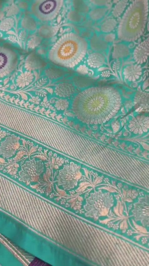 Turquoise Banarasi Handloom Katan Silk Saree with intricate multicolored chakram motifs and ornate zari borders.