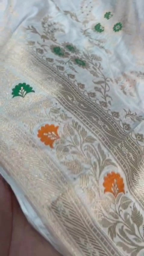 Ivory Banarasi Handloom Pure Katan Silk Saree with delicate floral vine zari pattern and green and orange Meenakari floral accents.