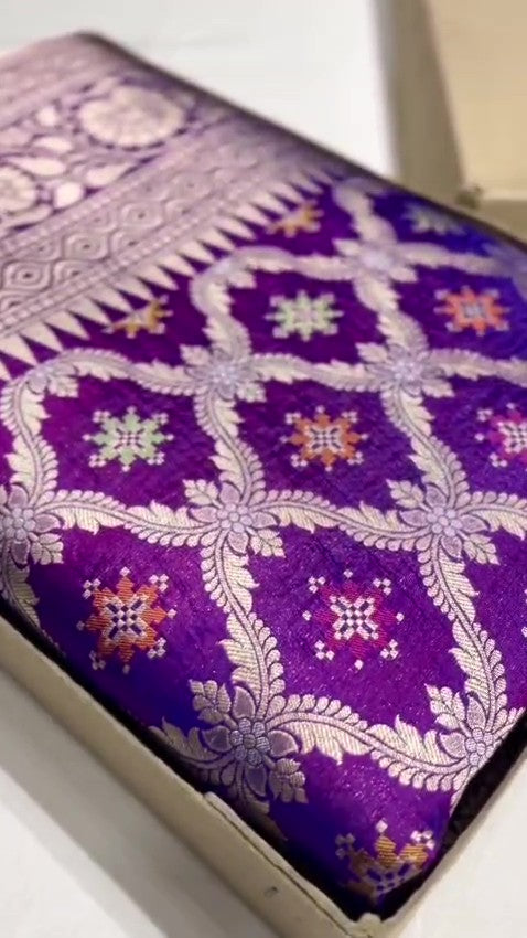 A deep royal purple Banarasi handloom pure Katan silk saree featuring vibrant multicolored Meenakari floral motifs and an elaborate silver zari border and pallu.