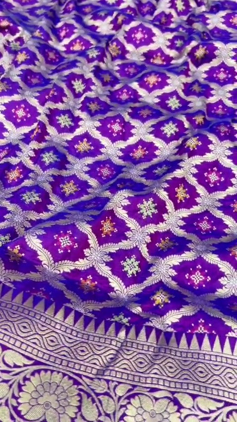 A deep royal purple Banarasi handloom pure Katan silk saree featuring vibrant multicolored Meenakari floral motifs and an elaborate silver zari border and pallu.