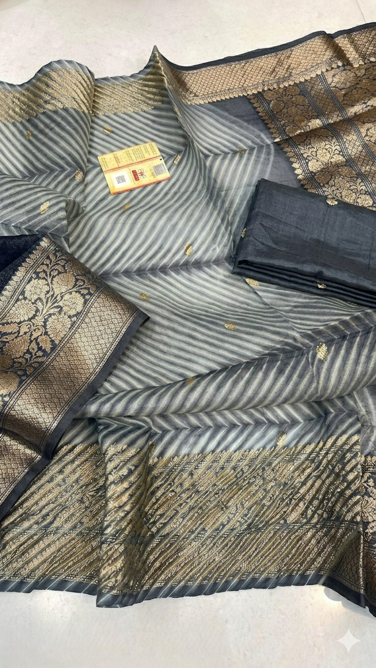Two models in an ethnic Banarasi courtyard wearing charcoal grey Kora Tissue silk sarees featuring diagonal Arasi Shibori patterns and gold zari borders.
